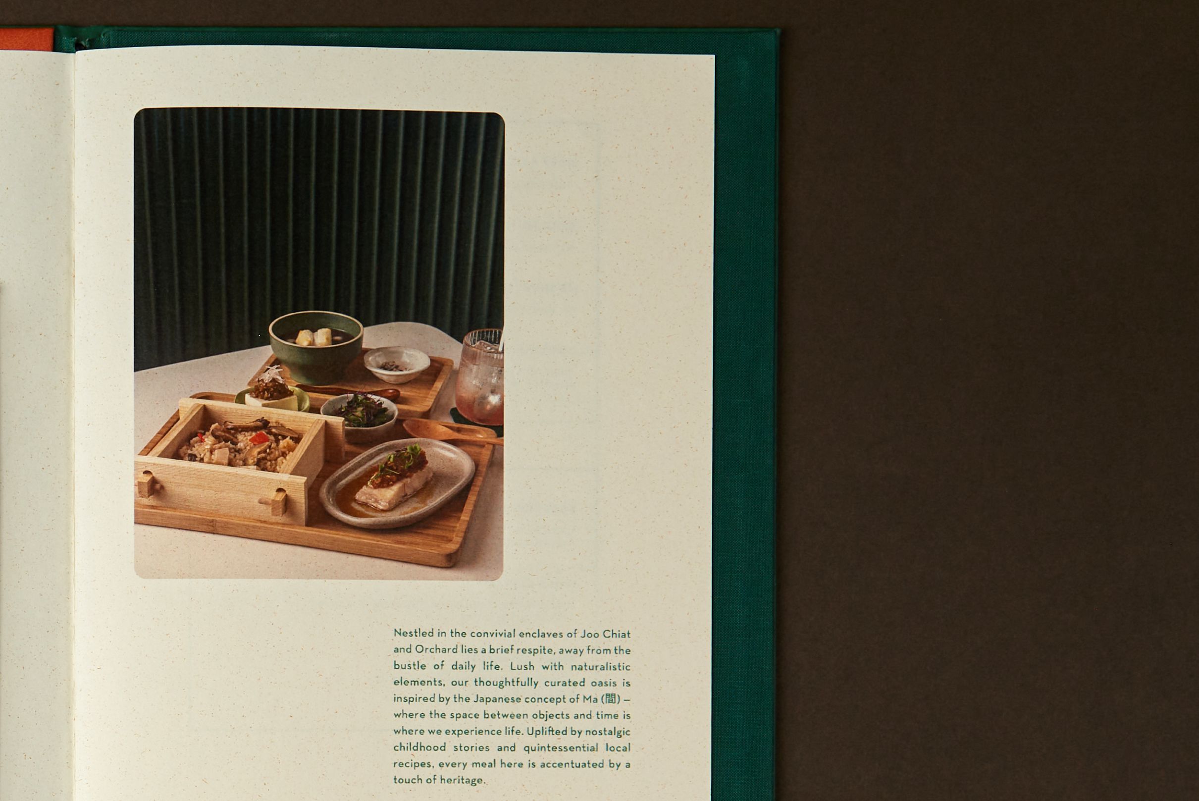 Open emerald Café Natsu menu showing an inside spread with a bento set food photograph and the brand story text