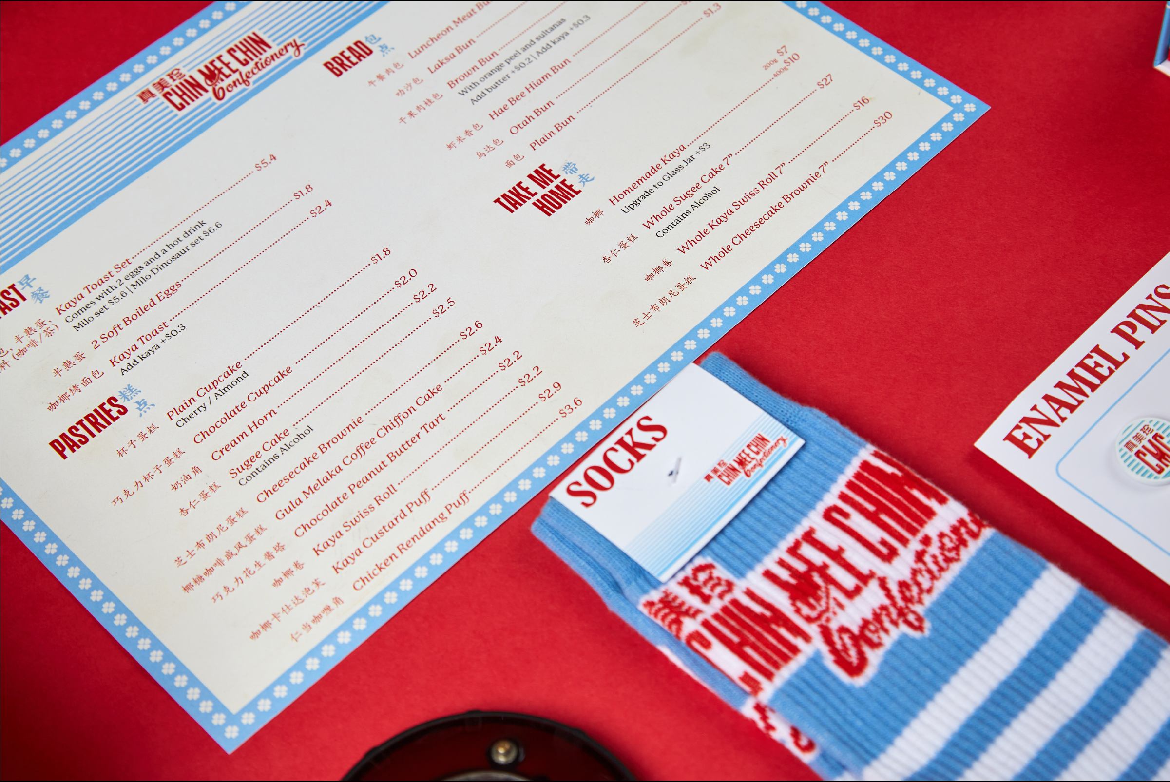 Menu and blue-striped CMC socks laid on red surface, showing bilingual Chin Mee Chin menu layout