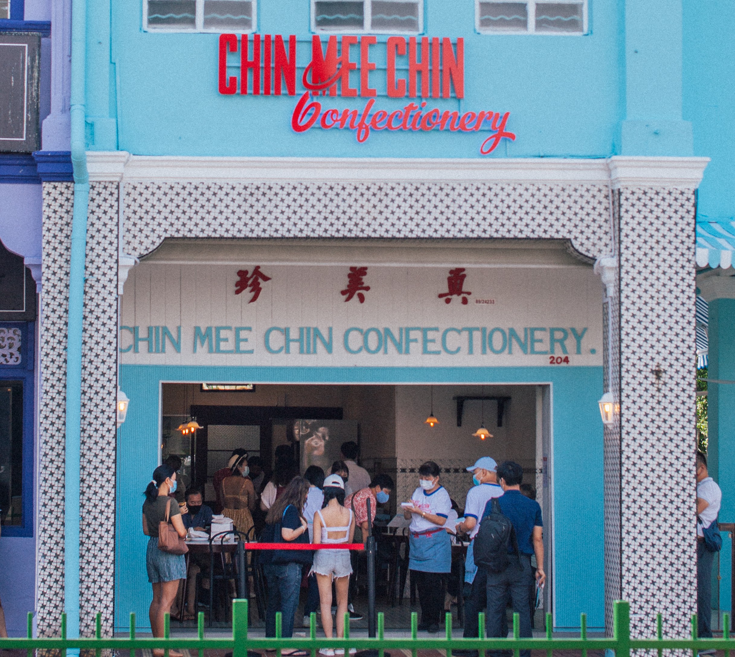 Chin Mee Chin Confectionery facade — sky-blue Peranakan shophouse with red neon-style signage, crowd queuing outside on East Coast Road