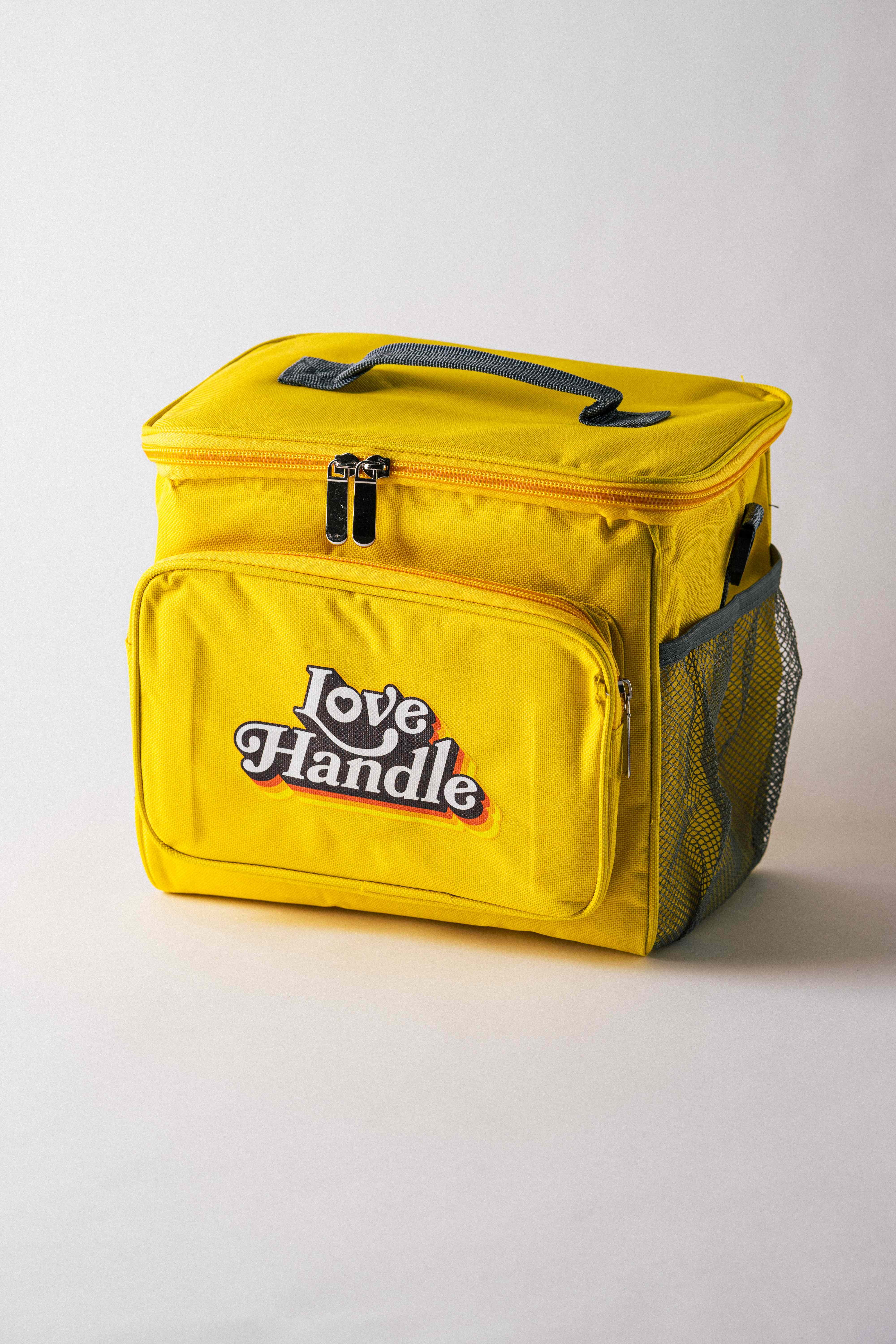 Yellow Love Handle branded soft cooler bag with the retro logo, grey handle and mesh side pocket, on a white backdrop