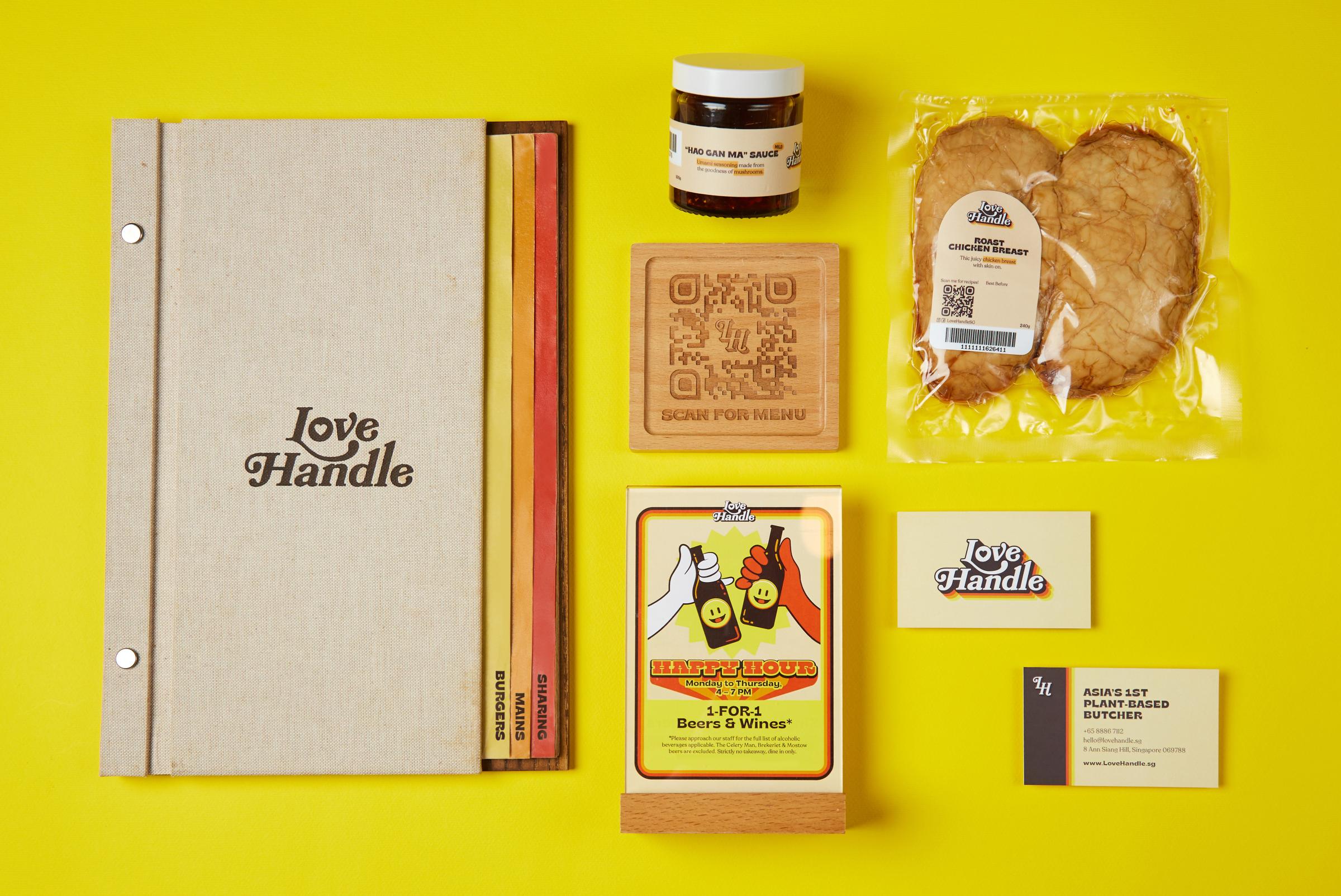 Full brand collateral suite on yellow — linen menu book with coloured tab edges, Hao Gan Ma sauce jar, wooden scan-for-menu coaster, roast chicken breast pack, happy hour table tent and business cards