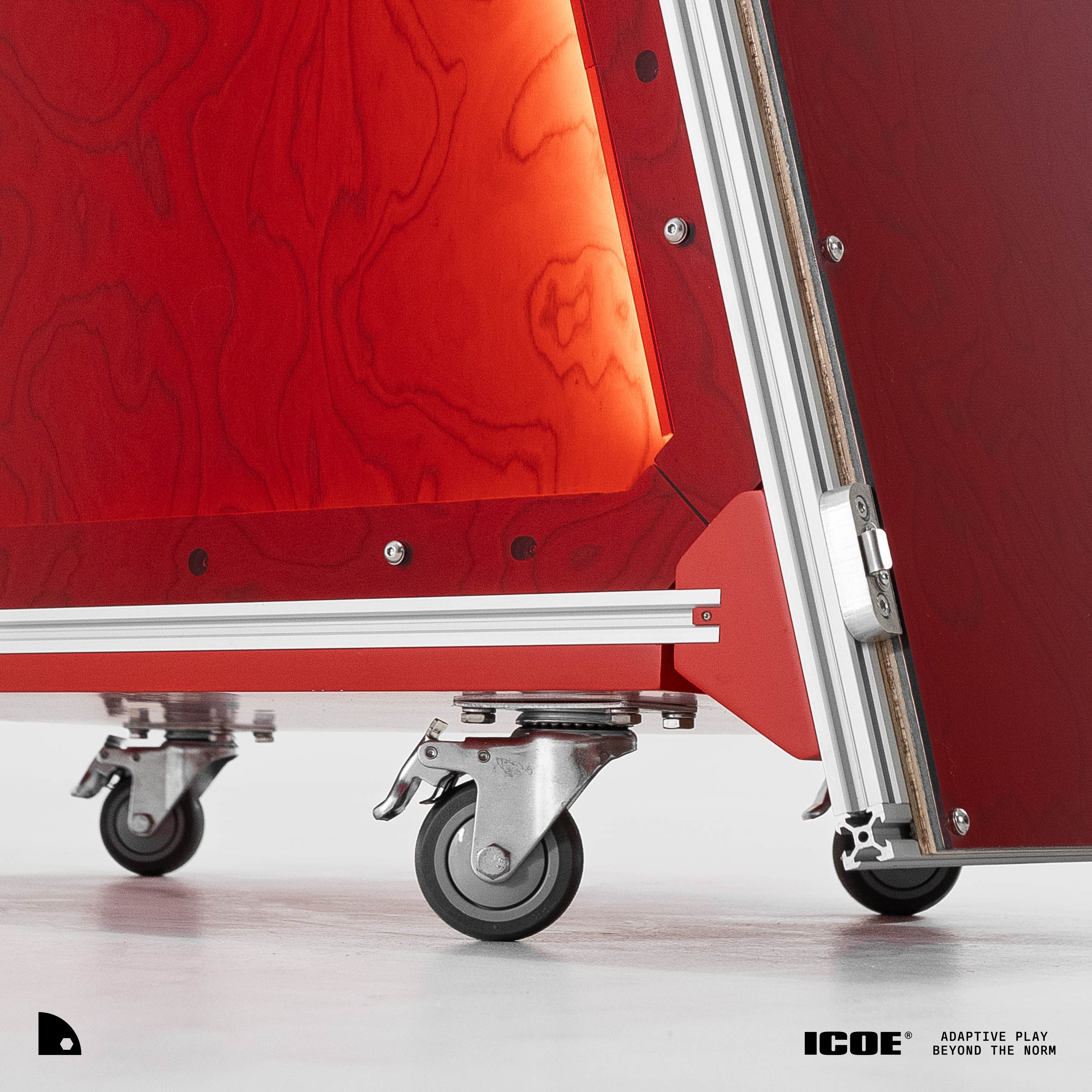 Close-up of the booth base — red woodgrain panels, aluminium extrusion rail and stainless locking swivel casters on a white floor