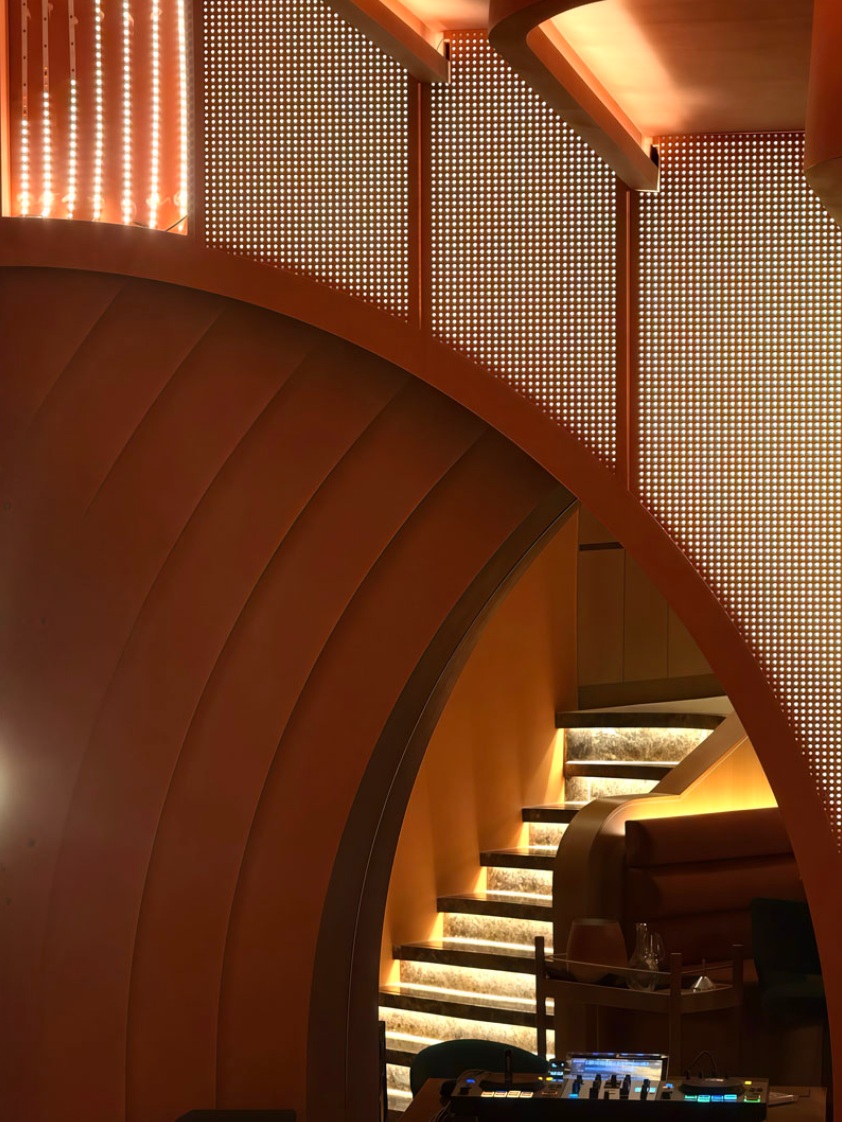 Sculptural curved staircase with a backlit perforated screen and softly lit marble steps
